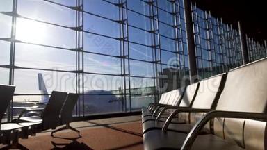 在阳光明媚的机场候机楼里的空椅子，飞机站在窗户后面，登机